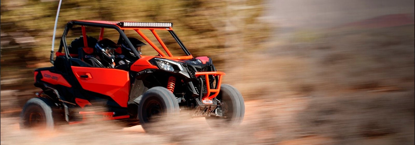 Rød ATV i fart på terreng med jord og støv, perfekt for fritidskjøring og utendørs eventyr.