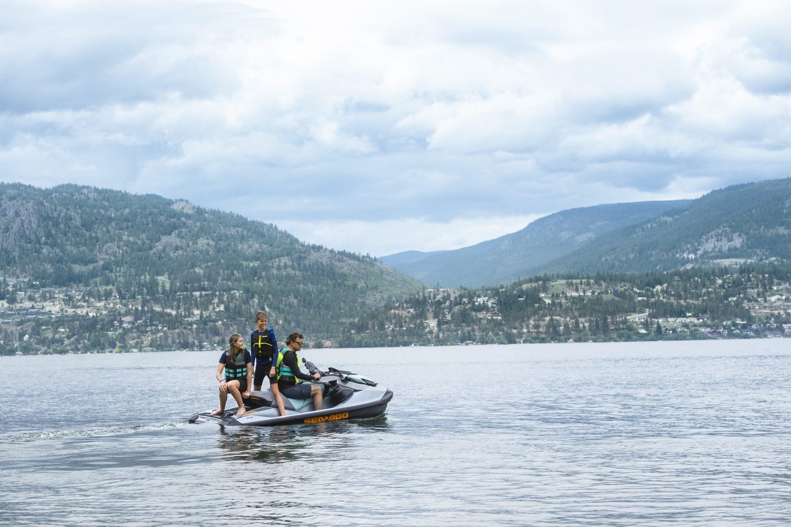 Bilde av tre personer på en Jet Ski i en innsjø omgitt av fjell, perfekt for fritidsaktiviteter og vannsport i Norge.