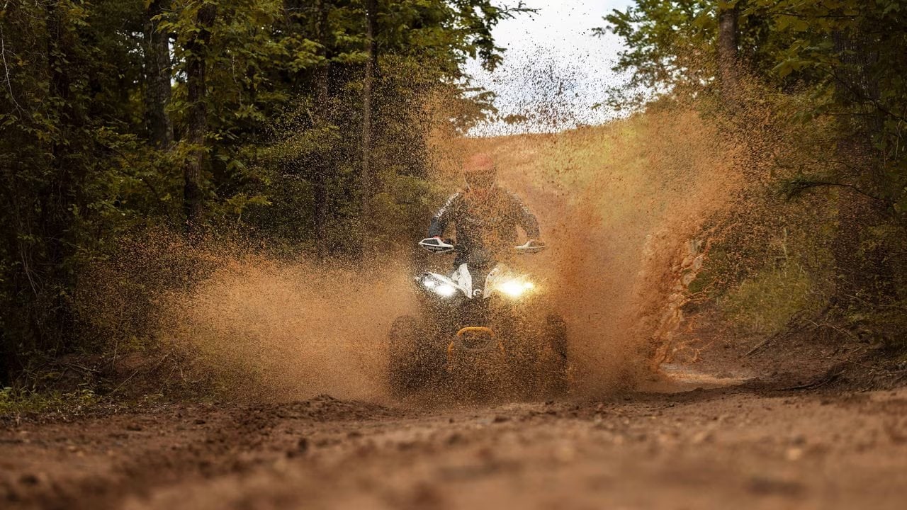 ATV kjører gjennom skog med støvskyer, offroad eventyr, fritid og motorsport i naturen.